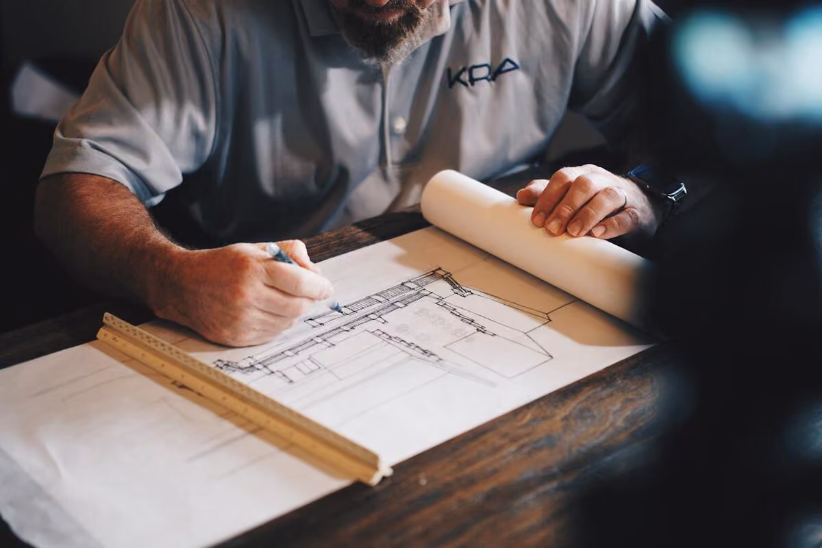 Architekt nanoszący poprawki na rysunku technicznym projektu domu przy biurku z linijką